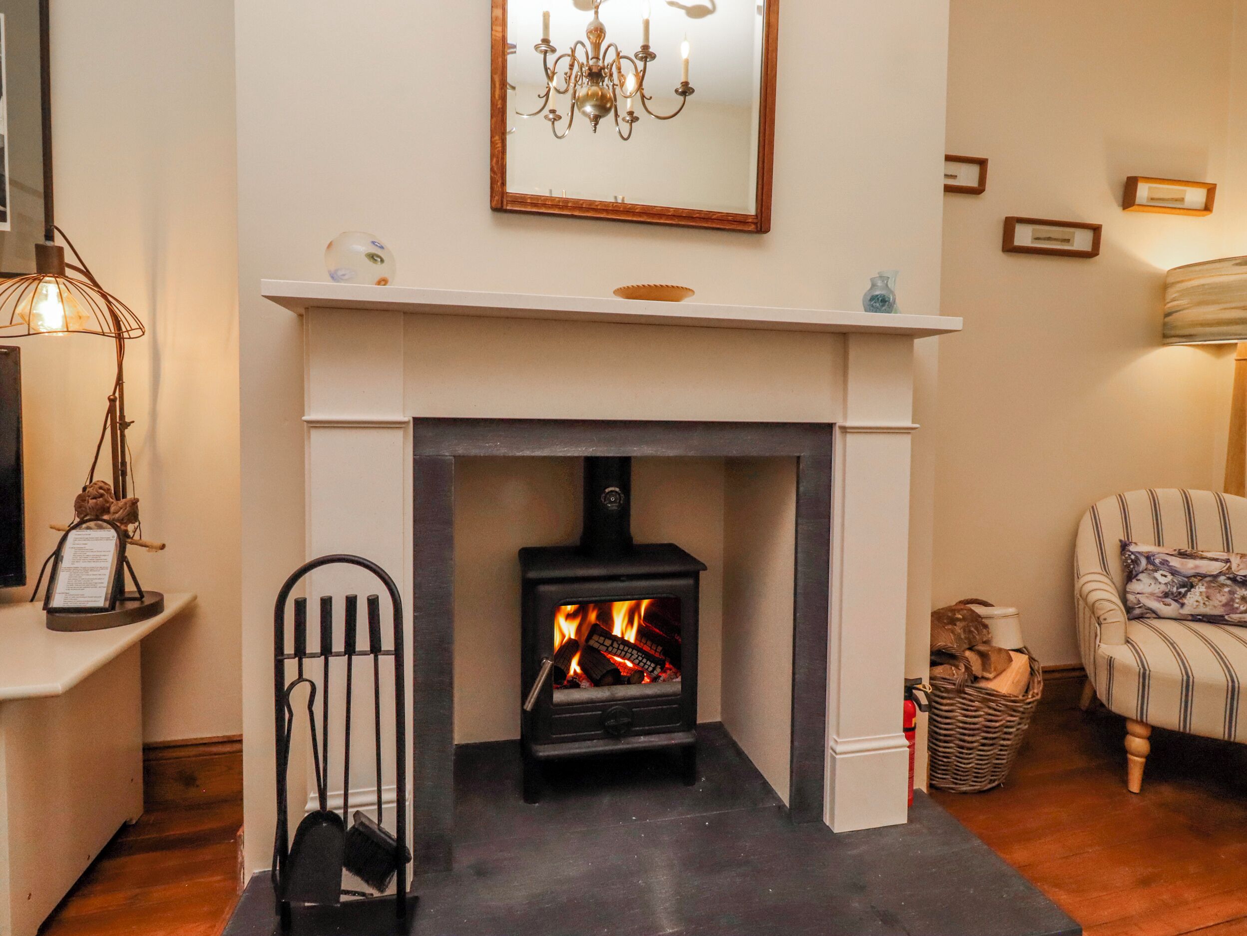 A fireplace with a modern design, a mantel with decorative items, and a chandelier above.