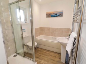 Un bany amb dutxa de vidre, vàter, banyera i un lavabo.