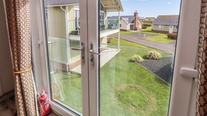 En bostadsbyggnad med en balkong, fri utsikt över det omgivande området och en gräsyta.
