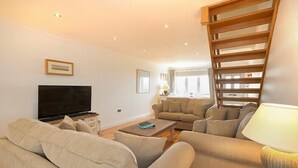 A living room with a TV, sofas, a coffee table, and a wooden slat structure. - Portland (Chathill)