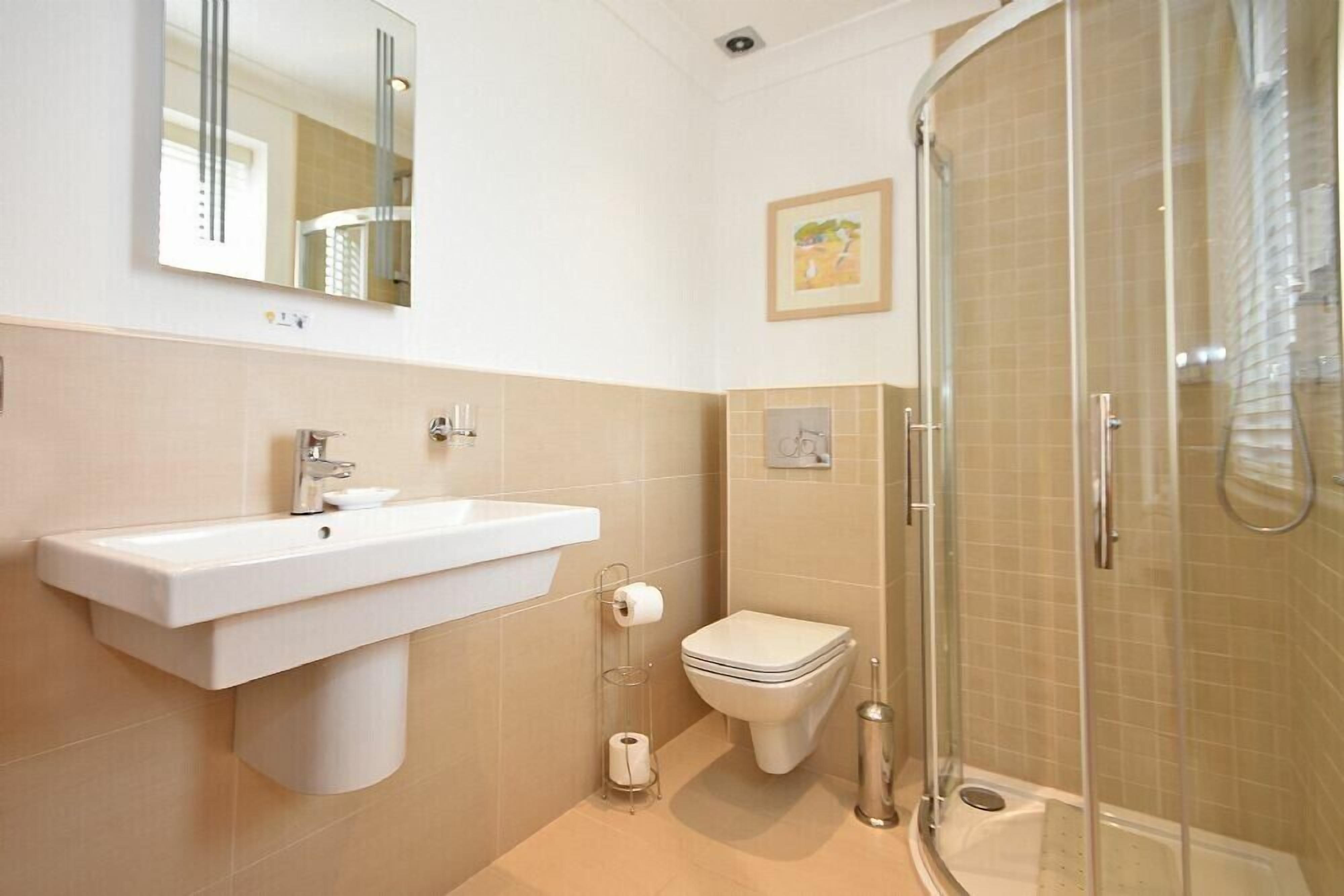 Une salle de bain  équipée d’un lavabo, de toilettes et d’une douche à parois de verre.