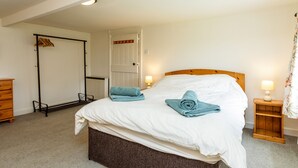 Ein Schlafzimmer mit einem Bett, zwei Nachttischen mit Lampen, einem Holzschrank und einem Kleiderschrank, sowie einer Tür.