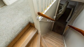 Eine Holztreppe mit Handlauf, Teppichwänden und einer Tür zu einem anderen Raum.