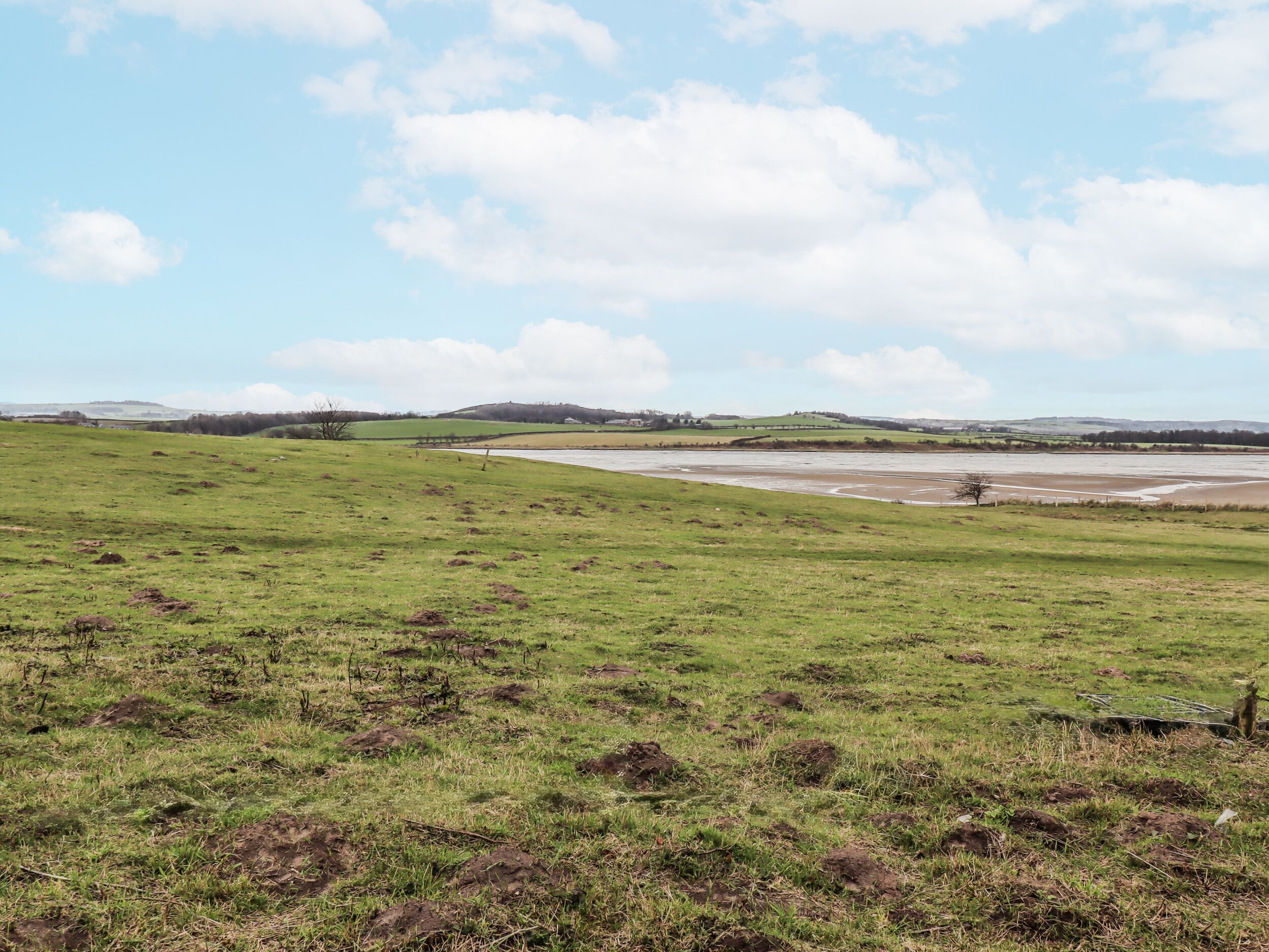 A wide, open field with a river in the distance and a clear sky.
