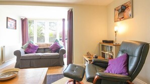 A cozy living room with a sofa, a chair, a coffee table, and a bookshelf. - Schooner Court No2 (Alnwick)