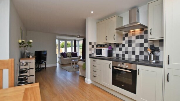 A modern kitchen with white cabinets, a black and white checkered backsplash, and a built-in oven. - Schooner Court No2 (Alnwick)