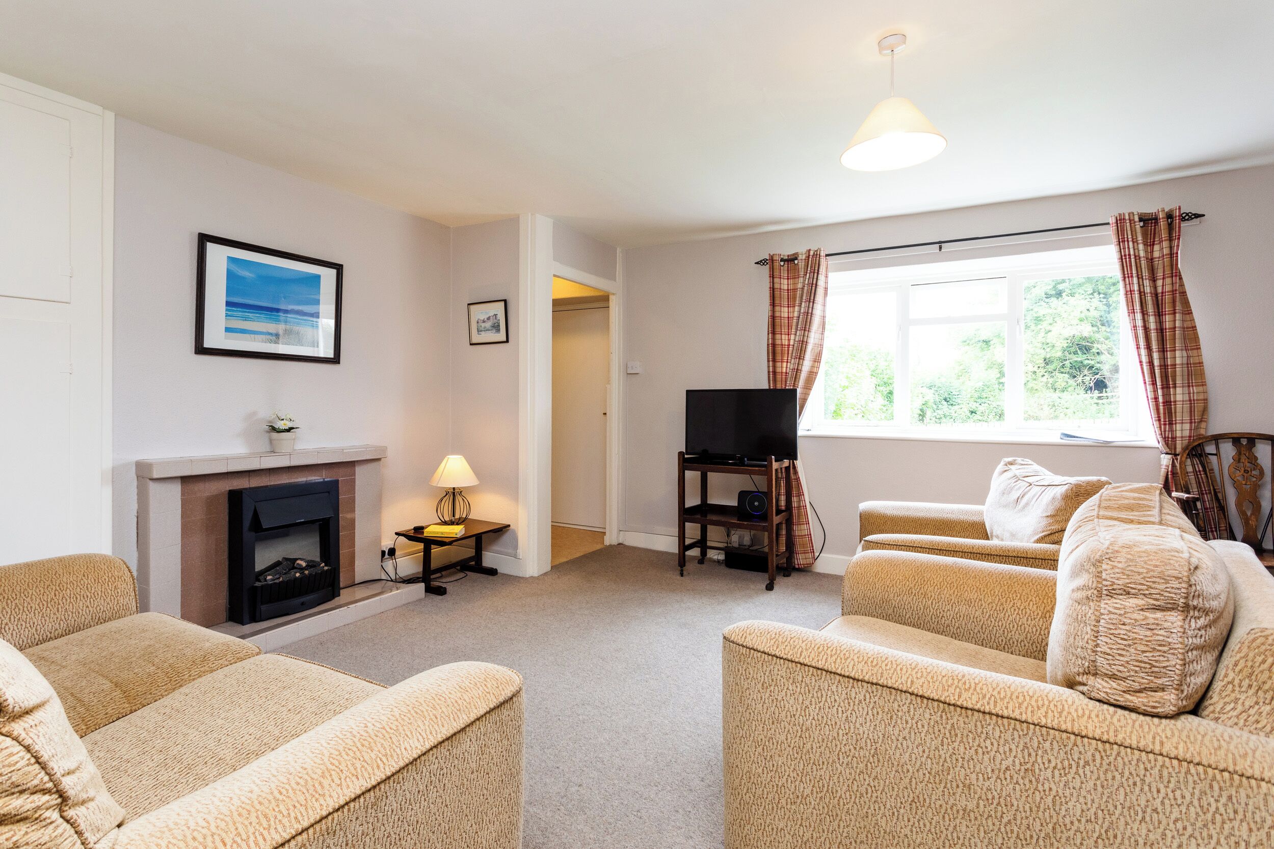 A living room with a fireplace, a television on a stand, and a window with curtains.