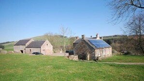 A rural property with stone buildings, a car, and a solar panel on one of the roofs. - Kirknowe (Hawick)