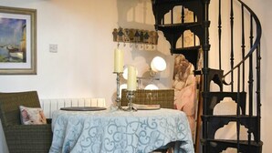A dining area with a table set for two, a chair, a staircase, and a wall-mounted coat rack.