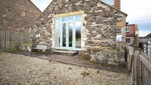 A stone cottage with a wooden fence, a bench, and a mailbox.