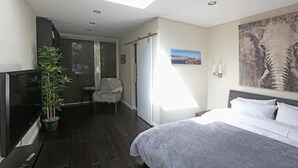 Una habitación de hotel moderna con una cama grande, televisión, planta en maceta y un cuadro de un elefante.
