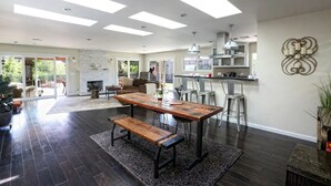 Amplia sala de estar con una mesa de comedor de madera, una chimenea y una cocina equipada con electrodomésticos modernos.