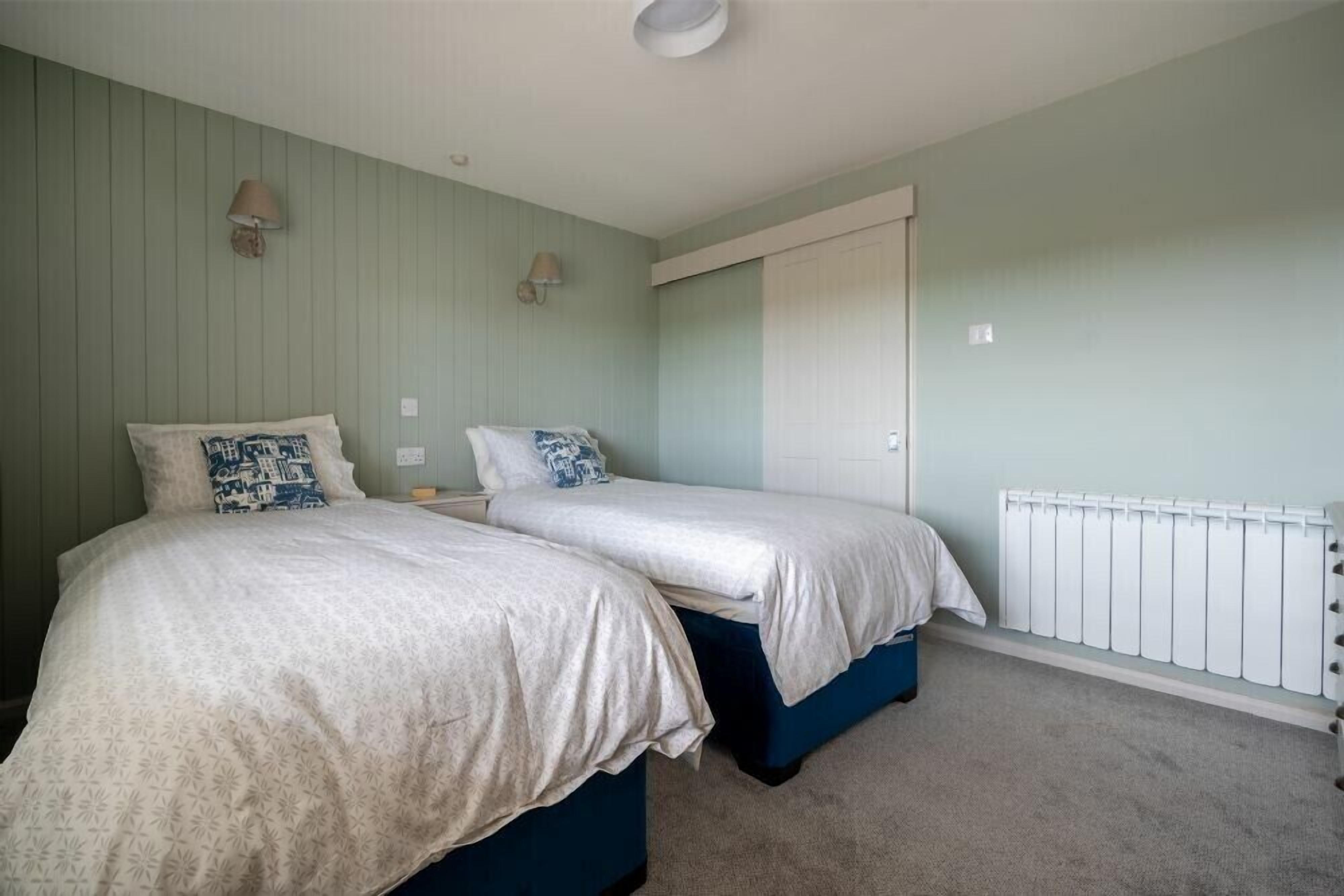 A bedroom with two beds, a radiator, and a door.