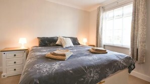 Una camera da letto con un letto, due comodini, una finestra con tende e un lampadario.
