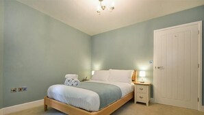 Quarto com cama, mesa de cabeceira, abajur e guarda-roupa.