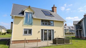 Ett tvåvåningshus med ett sluttande tak, solpaneler och en veranda på framsidan.