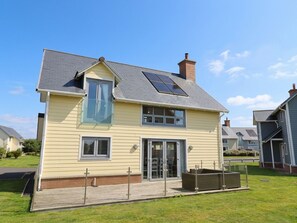 Ein zweigeschossiges Haus mit einem geneigten Dach, Solaranlagen und einer Veranda.