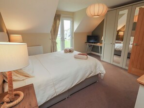 A bedroom with a bed, a desk, a television, and a wardrobe.