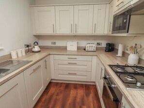 A compact kitchen with white cabinets, a toaster, a kettle, and a stove.