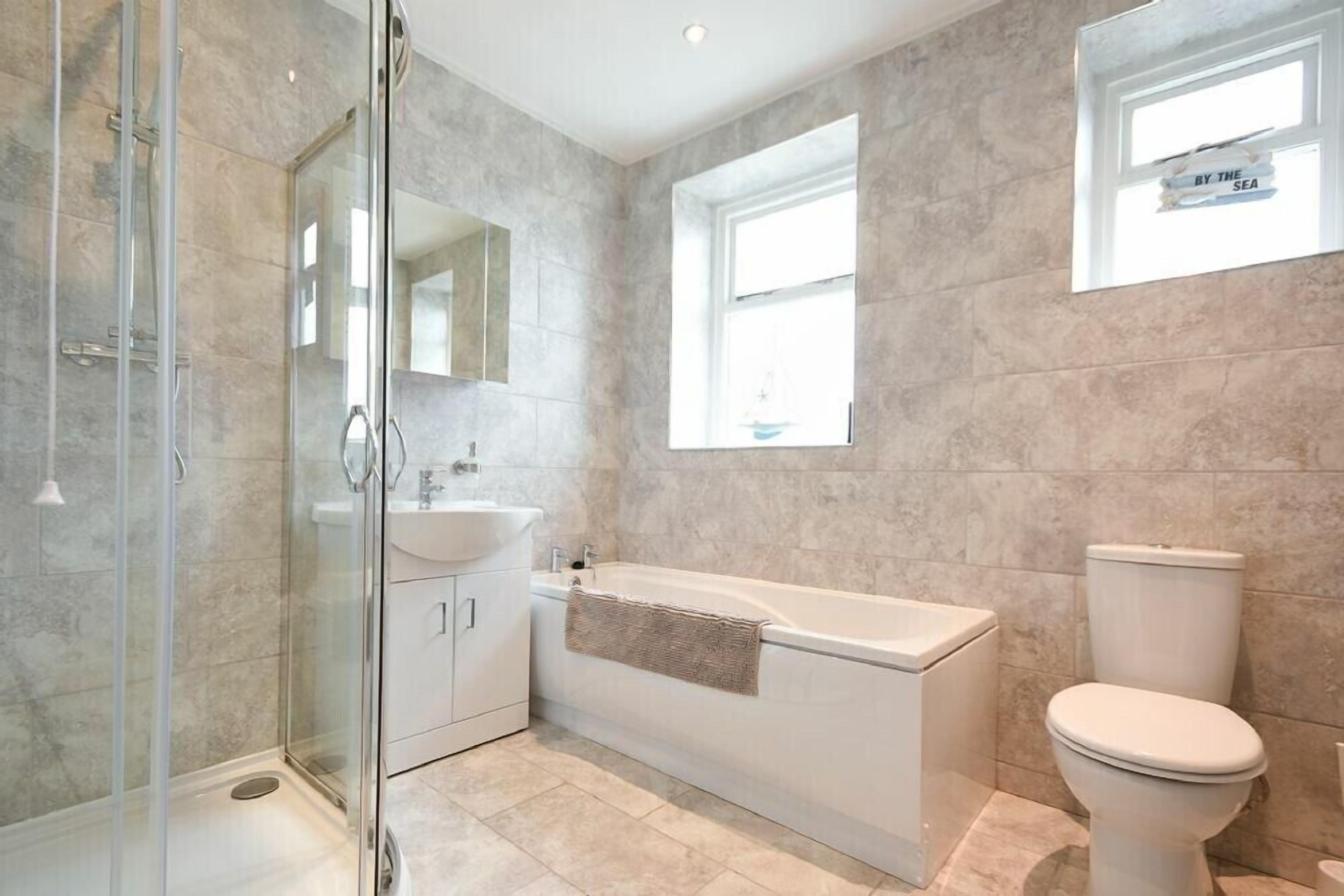 A modern bathroom with a glass-enclosed shower, a freestanding bathtub, and a toilet.