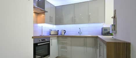 A modern kitchen with grey cabinets, a wooden countertop, and a built-in oven.