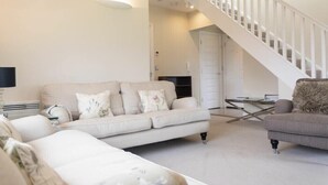 Ein modernes Wohnzimmer mit einer Couch, einem Sessel und einer Treppe.