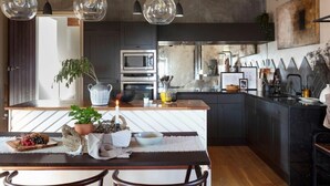 Una cocina moderna con armarios oscuros, una isla central e iluminación colgante.