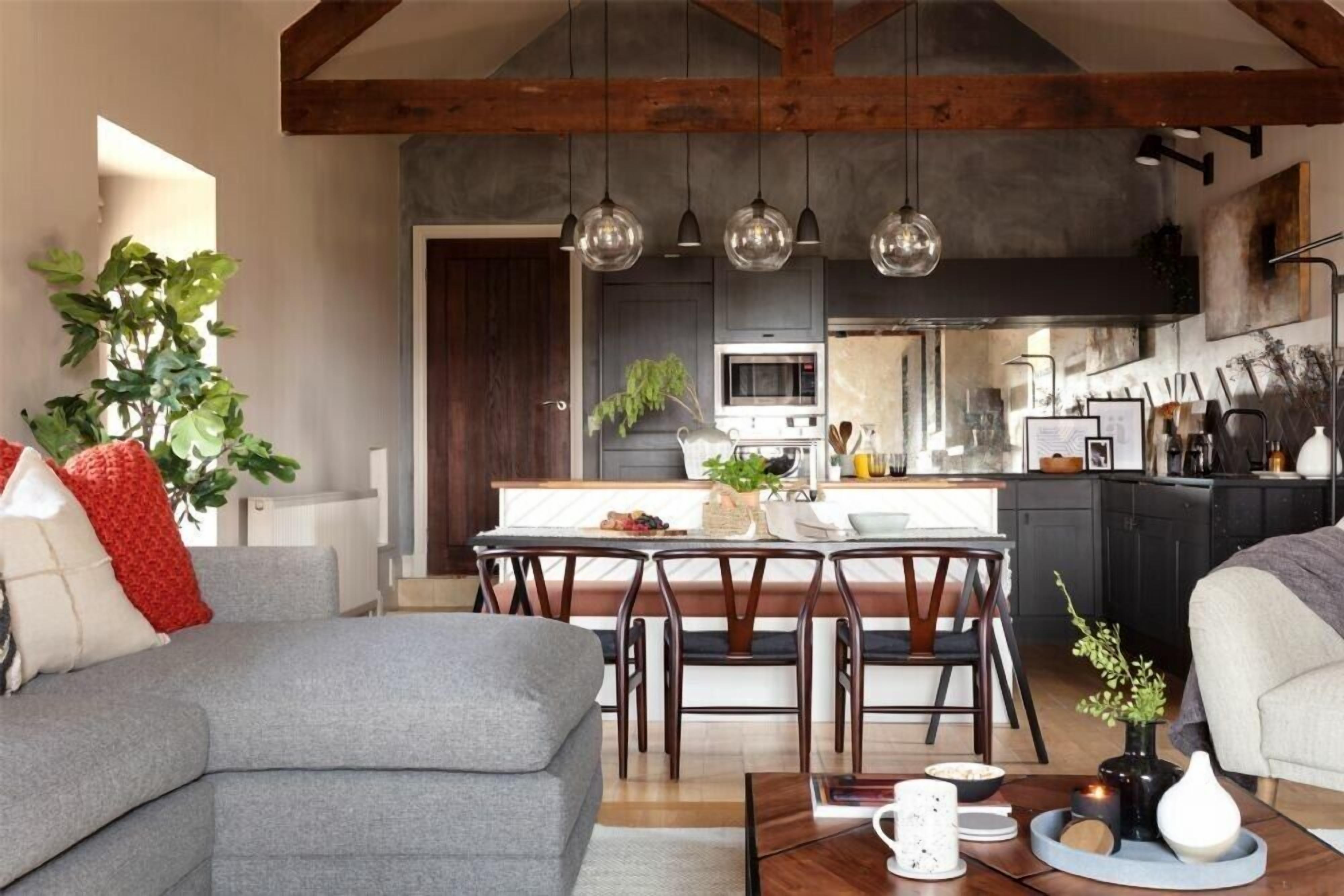 Een moderne keuken met een eethoek, met een grote eettafel, stoelen en hangende hanglampen.