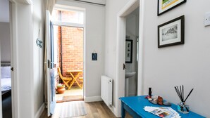A hallway with a blue table, a door leading to a patio, and a framed picture on the wall. - Baysyde (Alnwick)