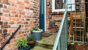 A brick exterior with a blue door, potted plants, and a wooden bench. - Baysyde (Alnwick)
