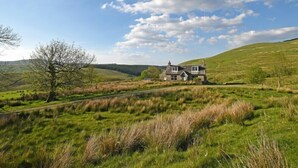 Une maison située sur une colline verdoyante, sous un ciel dégagé.