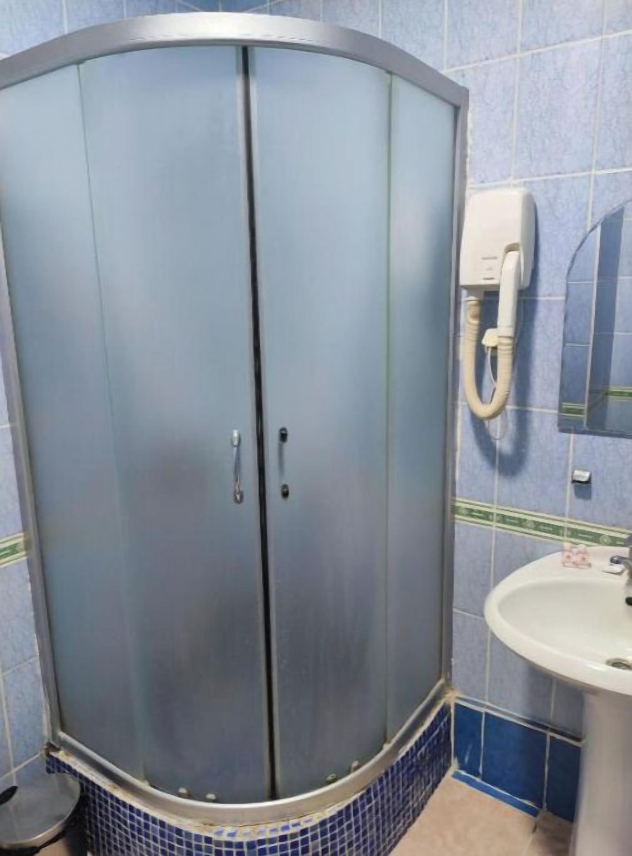 Un baño con cabina de ducha, lavamanos y secamanos.