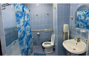 Bathroom features a bathtub, toilet, and sink, with a blue and white shower curtain.