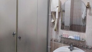 A bathroom with a shower enclosure, a sink, and a mirror. - Ikan Hotel twin room 11 (Tashkent)