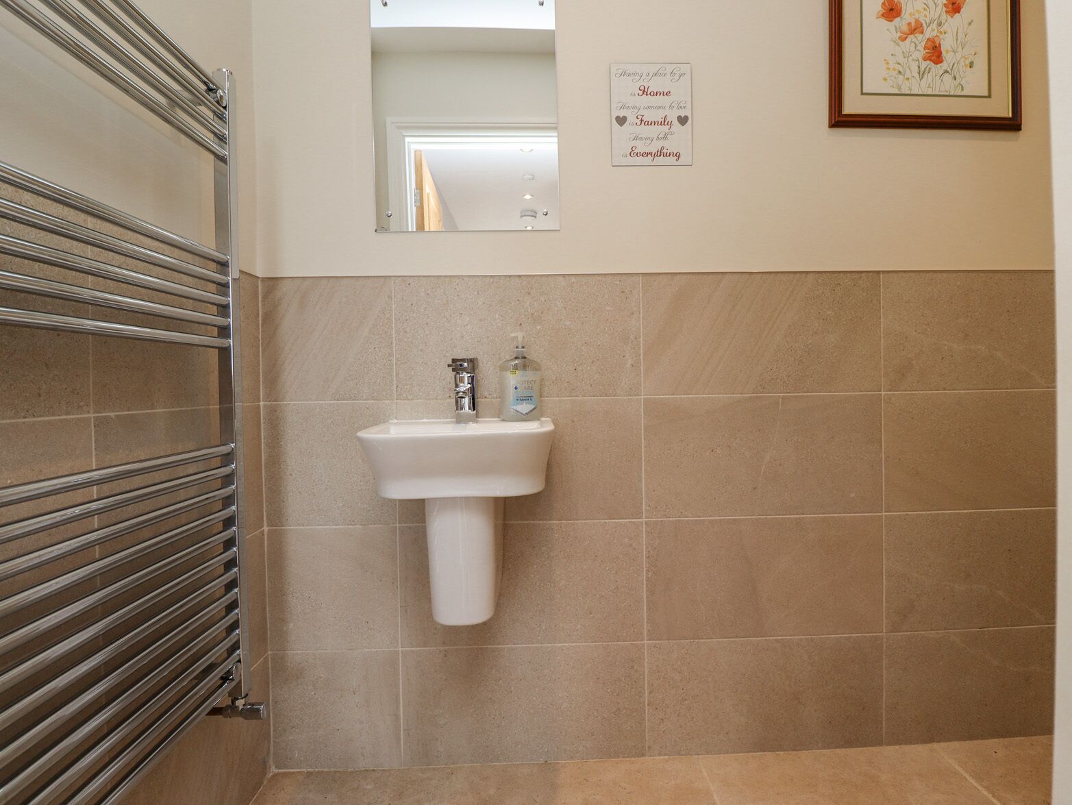 Une salle de bain avec un lavabo blanc, un distributeur de savon liquide et un miroir.