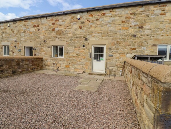 A stone building with a gravel courtyard, a door, and windows. - The Mustard Pot (Morpeth)