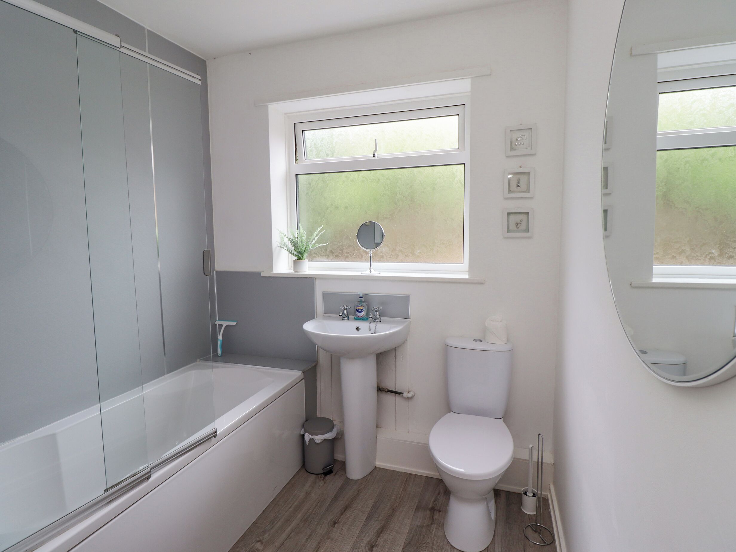 A bathroom with a bathtub, sink, toilet, and a window with a view of greenery.
