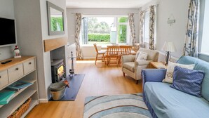 A living room with a fireplace, a television, a dining area with chairs, and a sofa. - Manor Cottage (Alnwick)