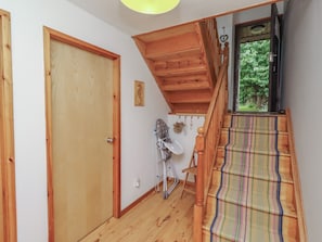 Una escalera de madera conduce a un segundo piso con una alfombra a rayas coloridas.