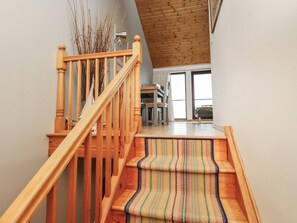 A wooden staircase with a woven carpet leading to a room with a view. - Links View (Alnwick)