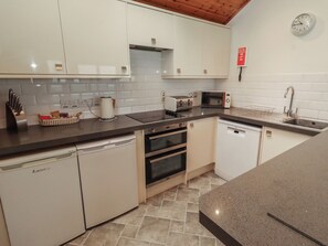 A modern kitchen with white cabinets, a microwave, toaster, kettle, and a dishwasher.