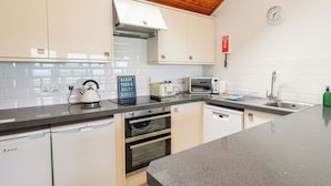 A modern kitchen with white cabinets, a granite countertop, a built-in oven, a microwave, and a sink.