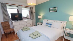 A bedroom with a bed, a television, a chair, and a nightstand. - Links View (Alnwick)