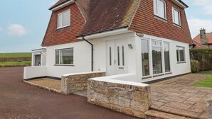A two-story house with a red-tiled roof, white exterior walls, and a stone foundation. - Whitestacks (Bamburgh)