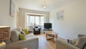 A modern living room with a sofa set, a coffee table, a TV, and a chandelier. - Coast View (Chathill)