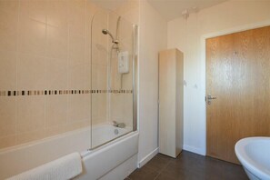 Une salle de bain avec une baignoire, un espace douche et une porte en bois.