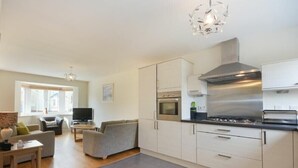 A modern kitchen with white cabinets, a stainless steel range hood, and a built-in oven. - Coast View (Chathill)