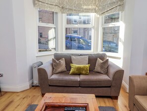 Ein Wohnzimmer mit braunem Sofa, einem Holztisch und einer Heizung.