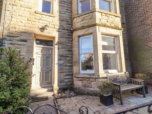 A stone building with a door labeled 'ALBERTBANK,' a window with a view, and a bench outside. - Alnbank (Alnwick)