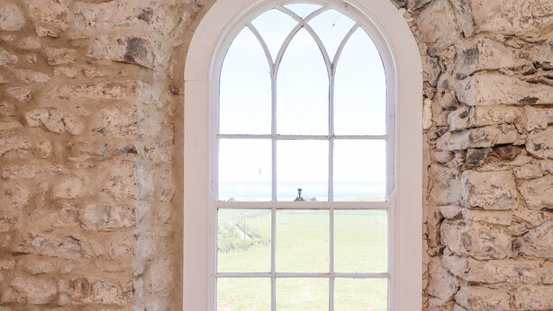 A stone wall with a large arched window. - The Lookout (Alnwick)